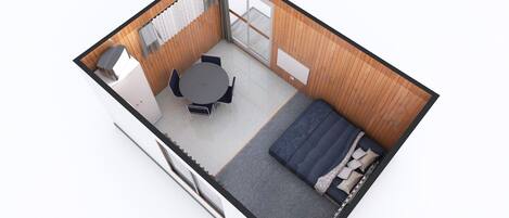 A compact room with a round table and chairs, a bed, and a sliding glass door leading to a balcony.