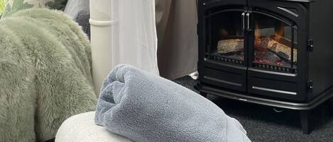 Una habitación con tienda de campaña acogedora, con una cama, un calentador pequeño negro, una lámpara y vistas a la vegetación.