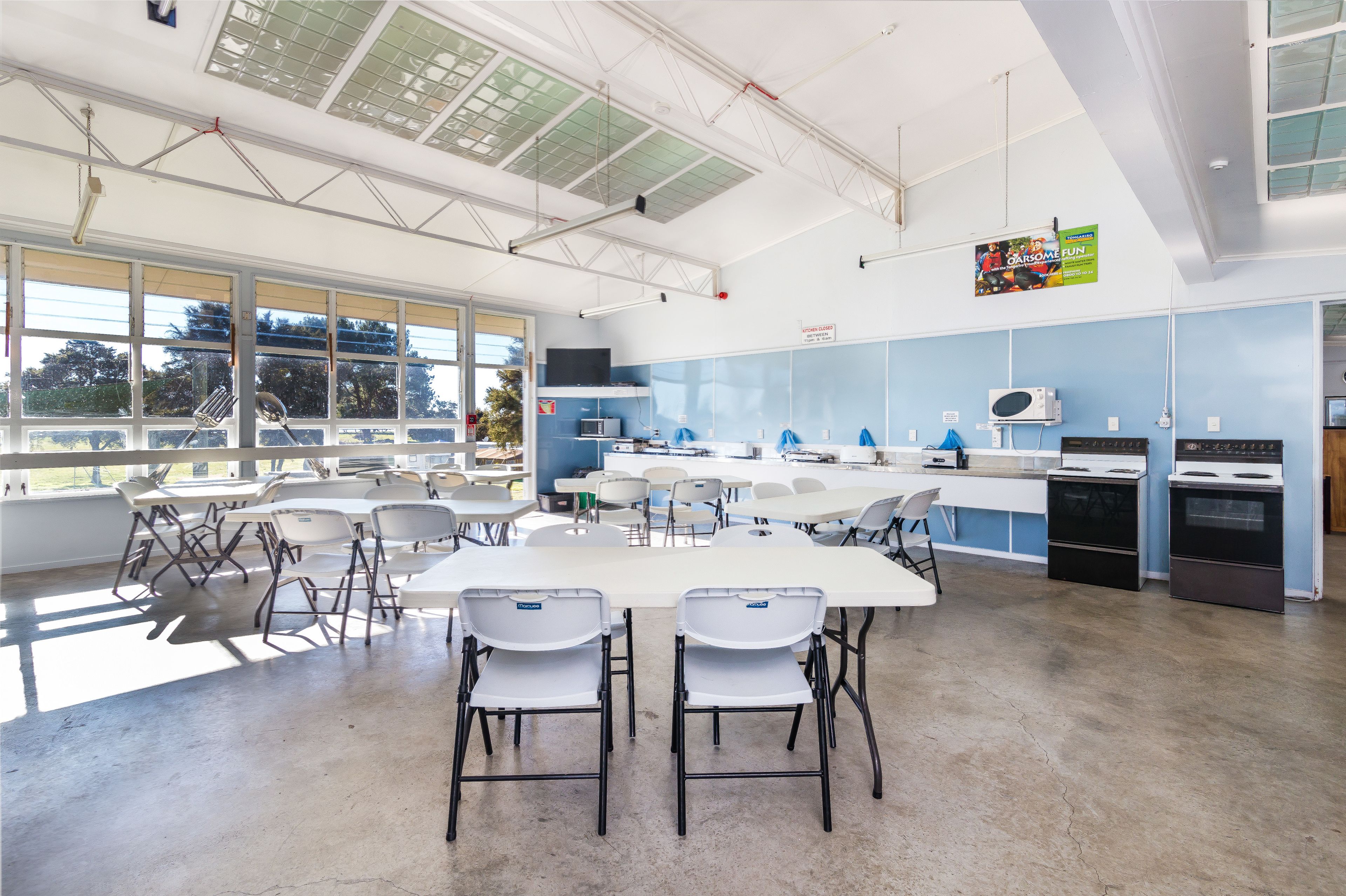 A modern kitchen with white countertops, stainless steel appliances, and ample natural light from large windows.