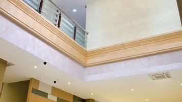 A hotel lobby with a reception desk, a chandelier, and a staircase.
