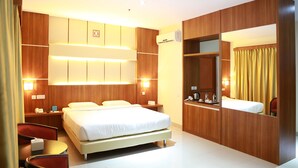 A modern hotel room with a large bed, bedside tables, a desk, and a mirror.