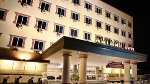 A hotel with multiple floors, large columns, and a well-lit entrance.