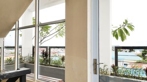 Un balcon doté de grandes fenêtres, d’une rambarde en métal et de plantes en pot.