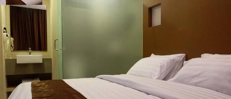 A hotel room with a bed, a bathroom with a sink, and a door leading to another room.