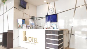 Un comptoir d’accueil d’hôtel équipé d’un écran numérique, d’une horloge et d’une enseigne indiquant le nom de l’hôtel.