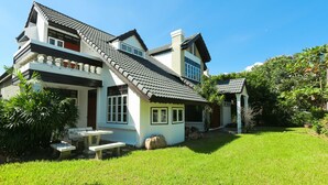 A two-story house with a tiled roof, a balcony, and a well-maintained lawn. - Villa de Nimman (Chiang Mai)