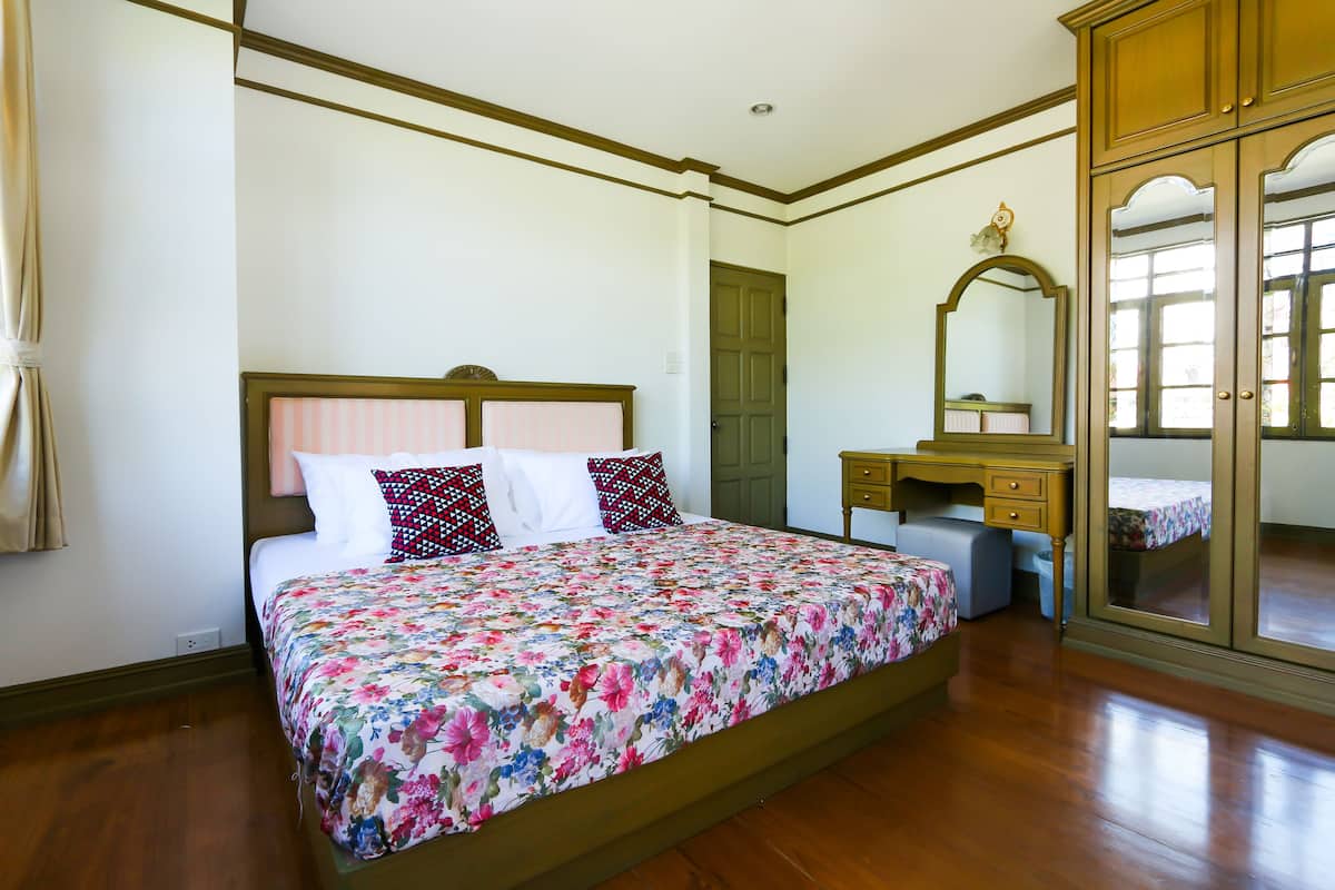 Un dormitorio con una cama grande, un aparador de madera y un espejo.