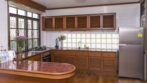 A kitchen with wooden cabinets, a stainless steel refrigerator, and a large island. - Villa de Nimman (Chiang Mai)