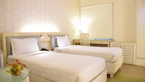 A hotel room with two beds, a desk, a chair, a lamp, and a mirror. - Fabhotel Check'in By Oran (New Delhi)