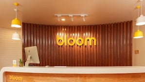 A reception desk with a wooden backdrop and the word 'bloom' in large letters. - Fabhotel Check'in By Oran (New Delhi)