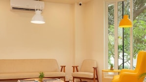 A living room with a sofa, chairs, a coffee table, and a window with greenery outside. - Fabhotel Check'in By Oran (New Delhi)