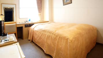 A hotel room with a bed, a desk, a chair, a mirror, a window with curtains, and a framed picture on the wall.