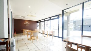 A hotel lobby with a large window, a reception desk, and several tables and chairs. - Royal Inn Mito (Mito)