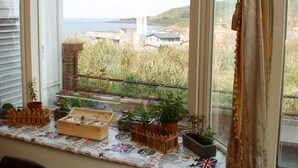 En balkon med plantekasser, havudsigt og en bygning i baggrunden.