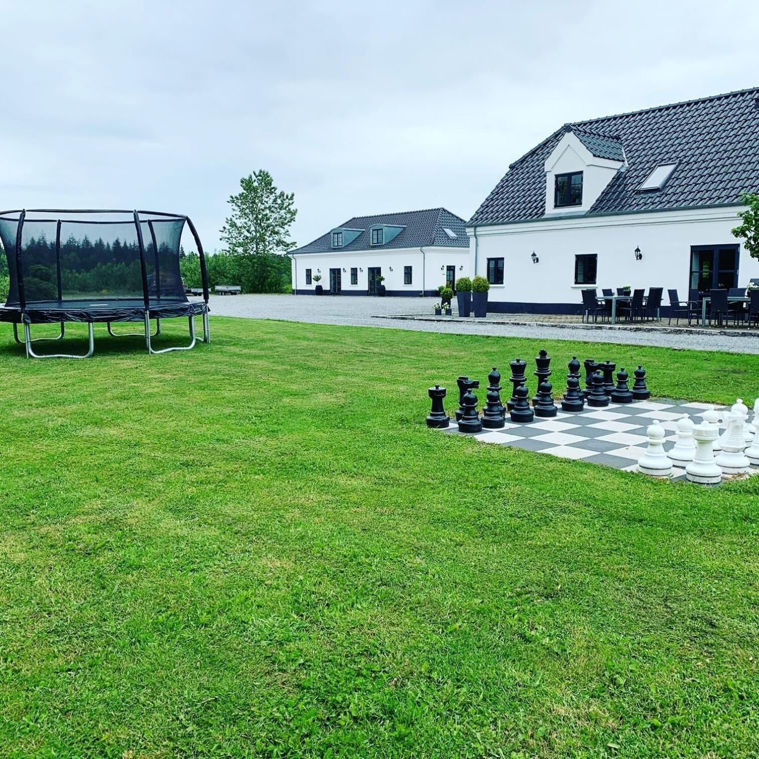 A large outdoor chess set on a grassy lawn with a white building in the background.