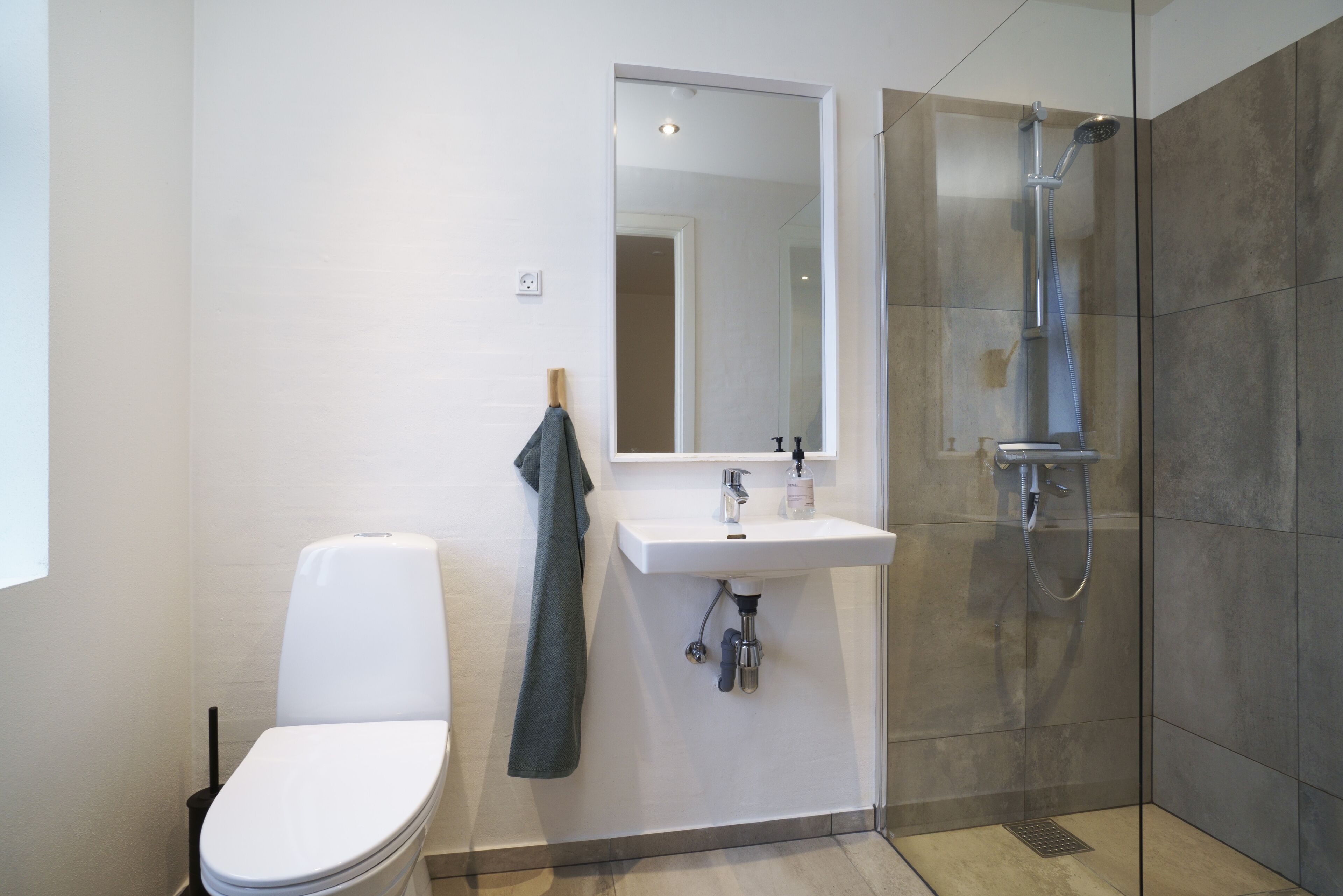 A modern bathroom with a toilet, sink, and shower.