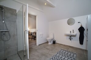Un baño moderno con ducha, inodoro, lavamanos y espejo.