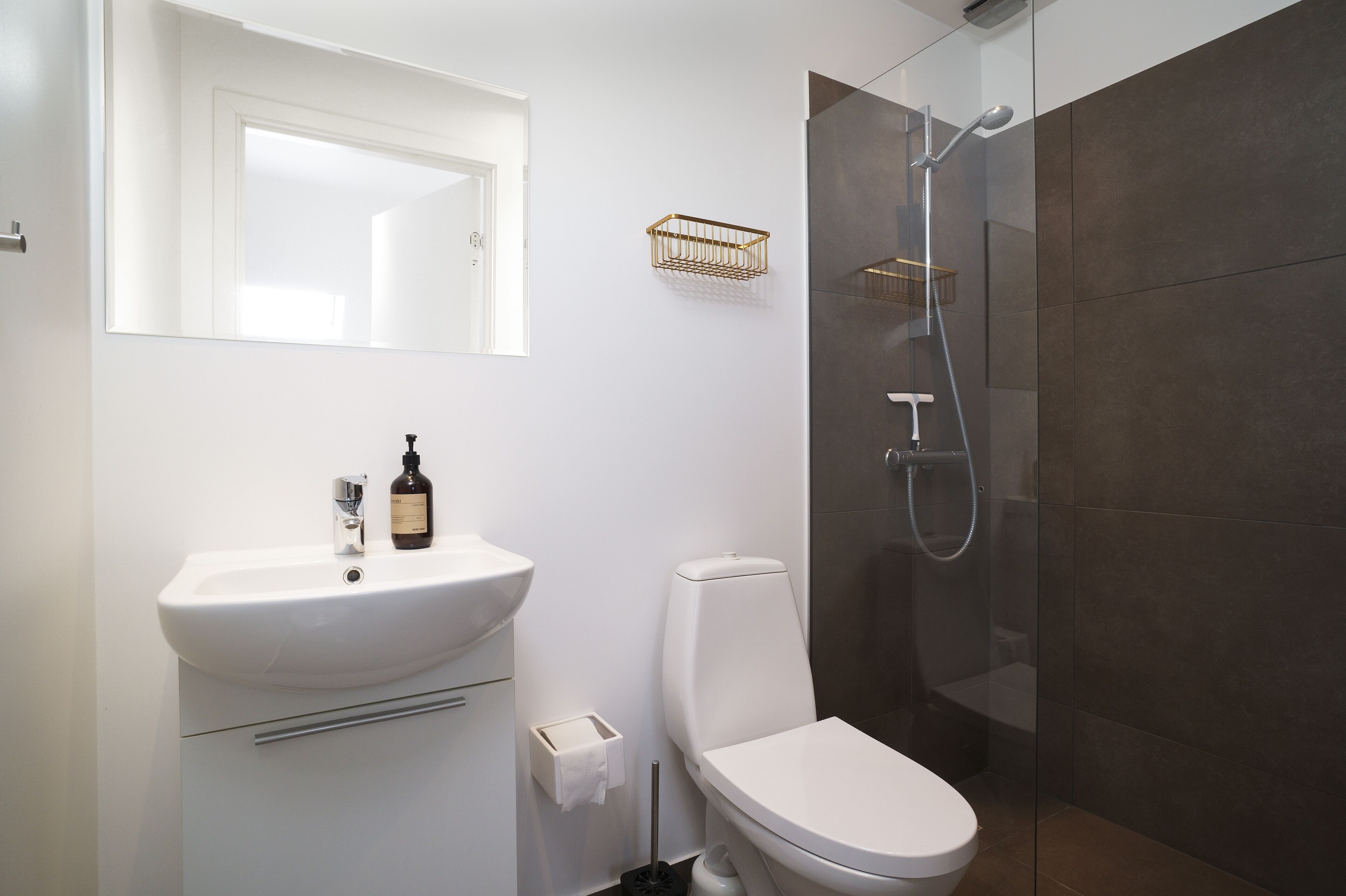 Une salle de bain moderne avec un lavabo blanc, des toilettes et une douche à parois de verre.