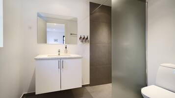 Un baño moderno con lavamanos, espejo y retrete blancos.