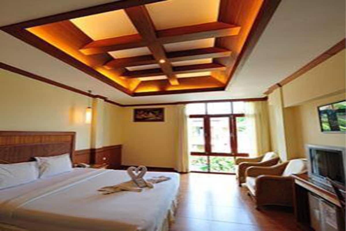 A hotel room with a bed, a TV, and a seating area.