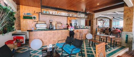 Zona de bar con un cartel de 'Welcome', asientos y una máquina de café.