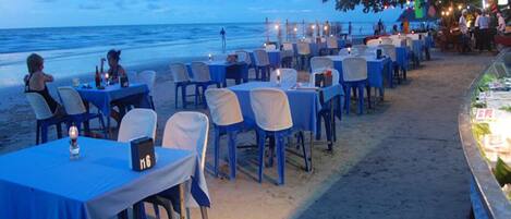 Un restaurante frente a la playa con mesas y sillas dispuestas para comer.