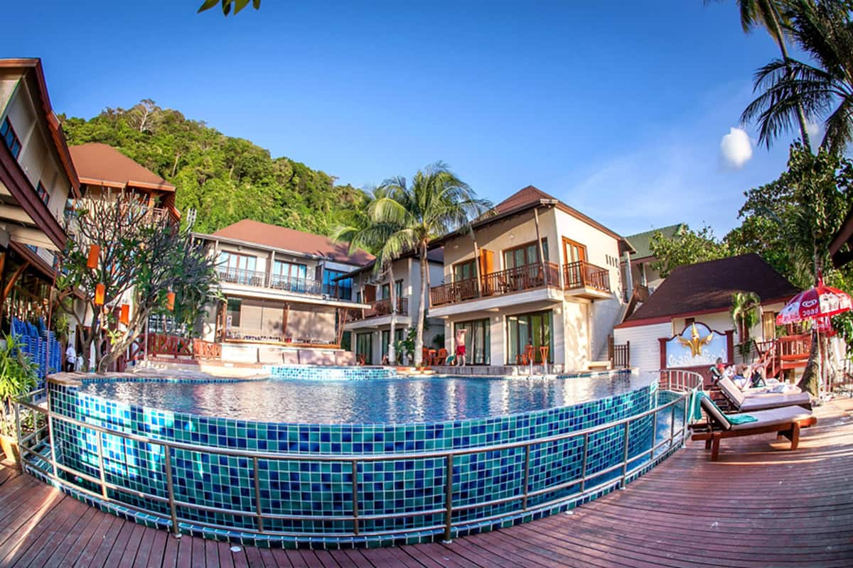 A resort with a central swimming pool, multiple balconies, and a wooden deck area.