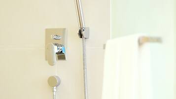 A shower with a handheld showerhead and a fixed wall-mounted faucet.