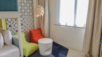 A modern room with a bed, a red chair, a white table, and a patterned wall.