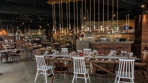 A restaurant with multiple dining tables and chairs, a bar area with bottles, and hanging light fixtures. - Hue Hotels and Resorts Puerto Princesa Managed by HII (Puerto Princesa)