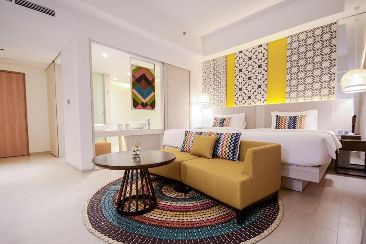 Ein modernes Hotelzimmer mit einer Couch, einem runden Tisch, einem Bett und dekorativen Wandverkleidungen.