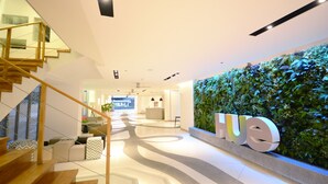 A modern hotel lobby with a staircase, a reception desk, and a green wall with the word "HUE". - Hue Hotels and Resorts Puerto Princesa Managed by HII (Puerto Princesa)