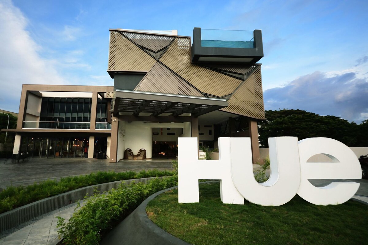 A modern building with a unique angular design, a glass atrium, and a large 'HUE' sign in front.