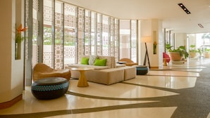 A spacious lobby with a sofa, ottoman, and decorative wall panels. - Hue Hotels and Resorts Puerto Princesa Managed by HII (Puerto Princesa)