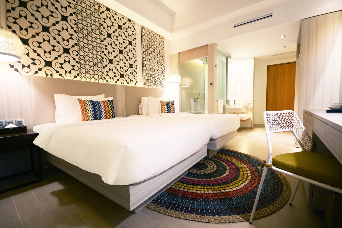 A hotel room with a large bed, a desk, a chair, and a bathroom visible through an open door.