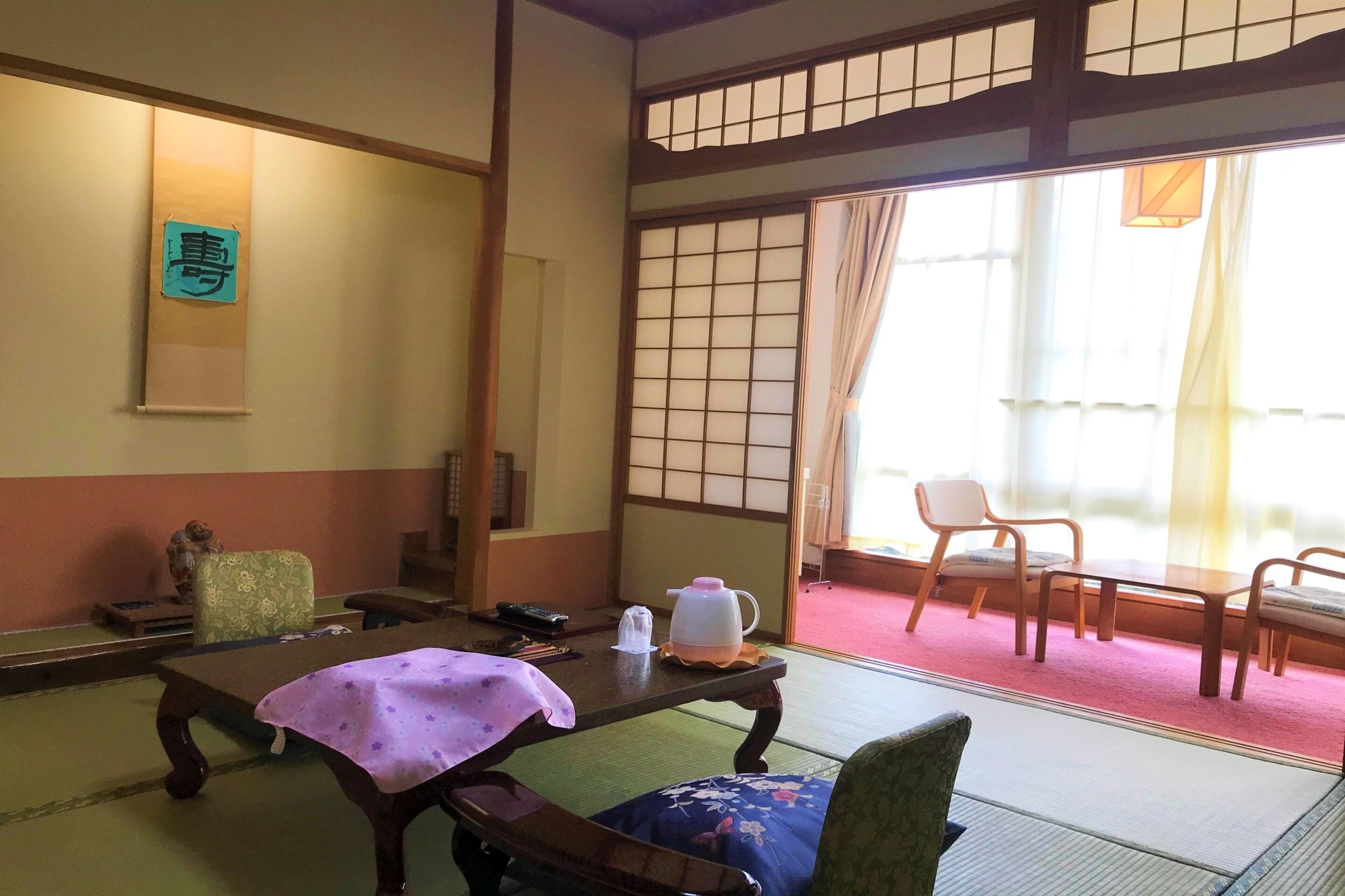 A traditional Japanese room with tatami flooring, a low table with a cloth, and a shoji screen door.