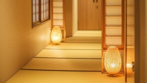 En traditionell japansk inredning med tatamimattor på golvet, skjutdörrar och en lampa som ger ett varmt, behagligt ljus.