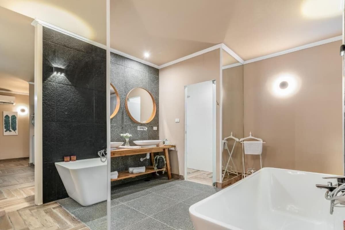 A modern bathroom with a freestanding bathtub, a vanity with a mirror, and a shower area.