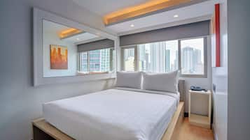A modern hotel room with a large bed, a bedside table, a mirror, and a city view.