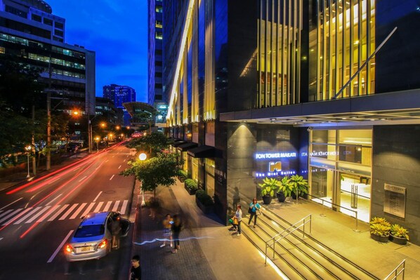 A modern hotel with a prominent entrance, a visible staircase, and a well-lit street view. - The Mini Suites - Eton Tower Makati (Makati)