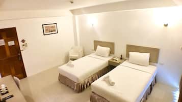 Habitación de hotel con dos camas individuales, un escritorio pequeño, una silla y una puerta.
