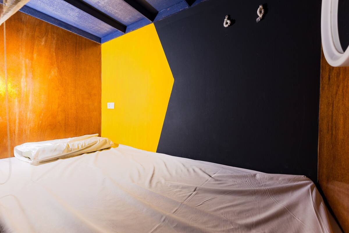 A hotel room with a bed, a yellow and black wall, and a wooden headboard.