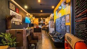 A cozy interior with a reception desk, seating area, and a wall of wine bottles. - Wire Hostel Patong (Patong)