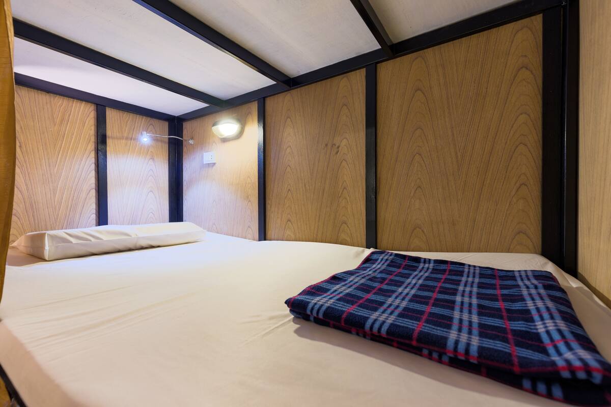 A bedroom with a bed, a bedside table, and a wall-mounted light.