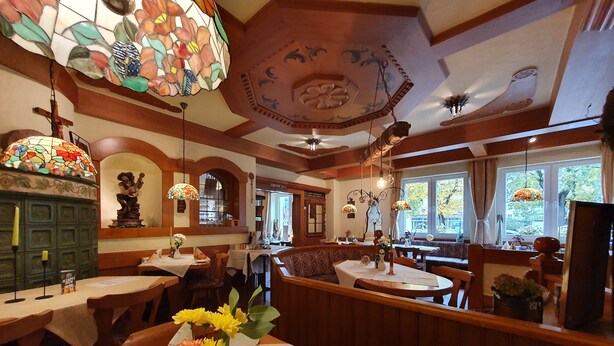 Un restaurant avec des banquettes en bois, des vitraux et une variété de décorations de table.