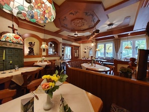 A restaurant with wooden booths, stained glass windows, and a variety of table settings. - Hotel Neuenburger Hof (Neuenburg am Rhein)