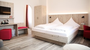 Une chambre d’hôtel moderne avec un lit en bois, un téléviseur à écran plat, un bureau et une chaise rouge.