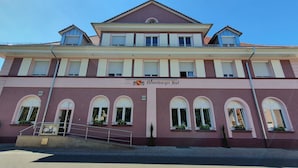 Un hôtel à la façade rouge, doté de nombreuses fenêtres et d’une enseigne indiquant « Hôtel-Restaurant ».
