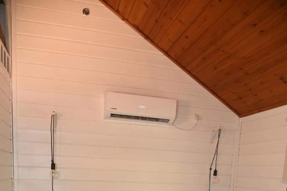 Ein Schlafzimmer mit Bett, einem Sessel, einer Klimaanlage und einer Holzbalkendecke.