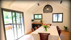 Un espace repas comprenant une longue table, des chaises et un luminaire suspendu.